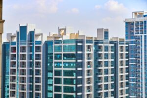 A cityscape view of modern high-rise buildings with reflective glass facades under a blue sky.