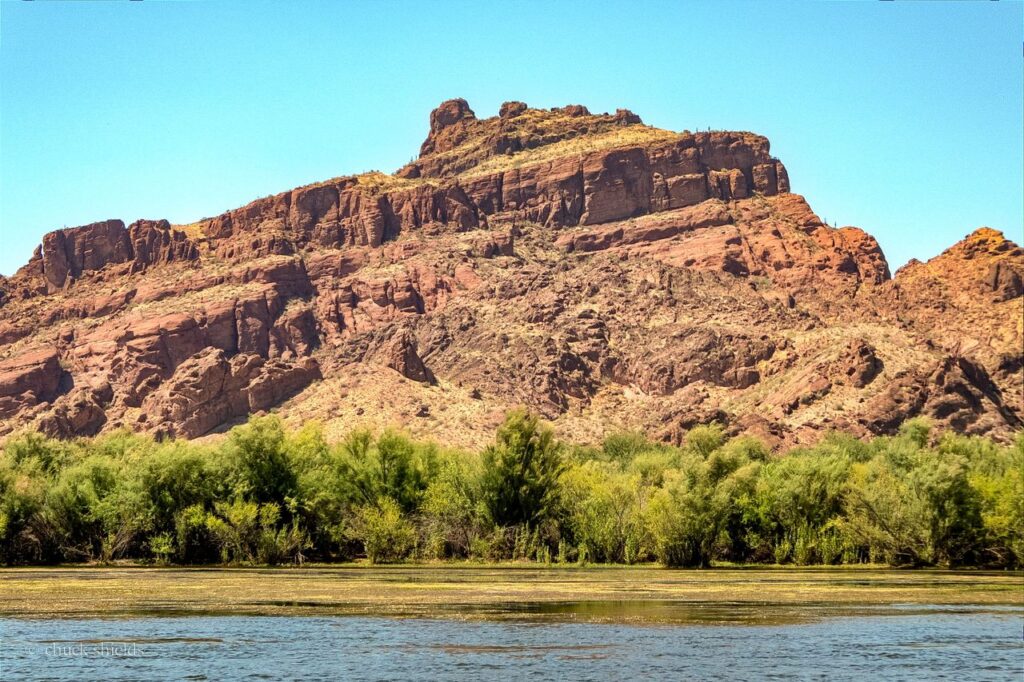 Scenic view of red rock cliffs by the Salt River in Mesa, Arizona under a clear blue sky.
