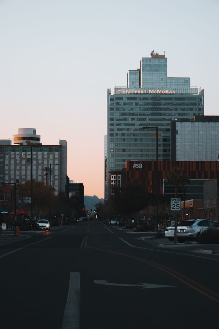 Urban cityscape at dusk featuring towering skyscrapers and a tranquil street view.