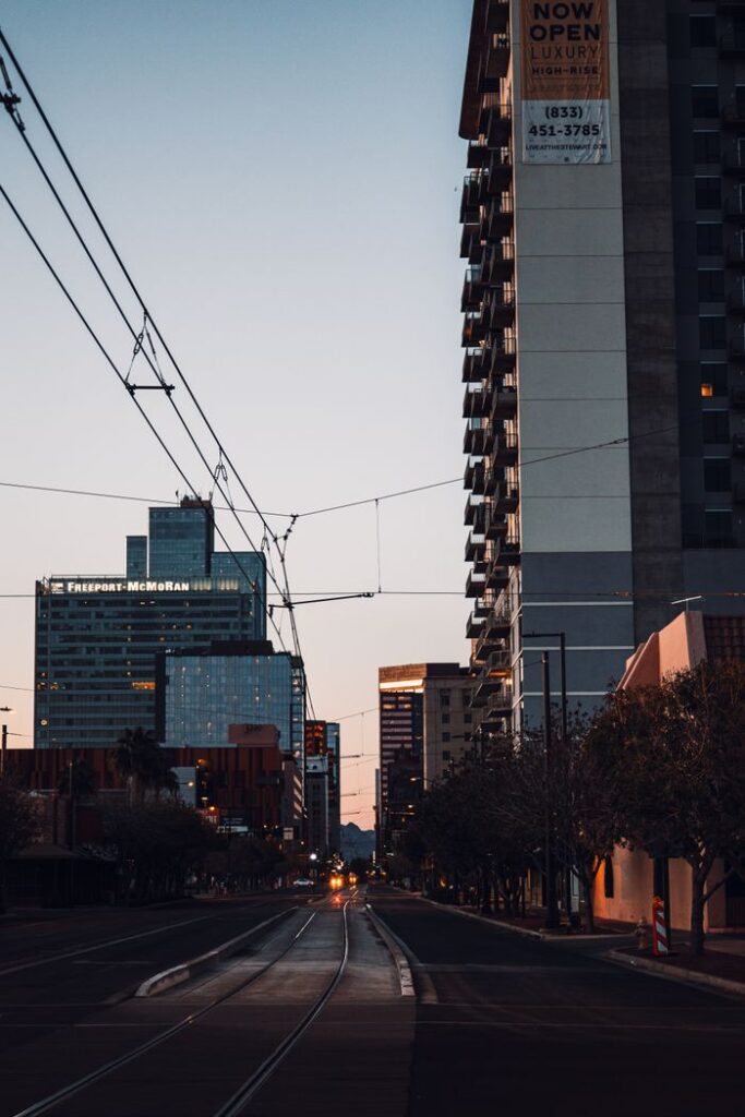 A city street with towering buildings and a sunset sky, creating a moody urban vibe.