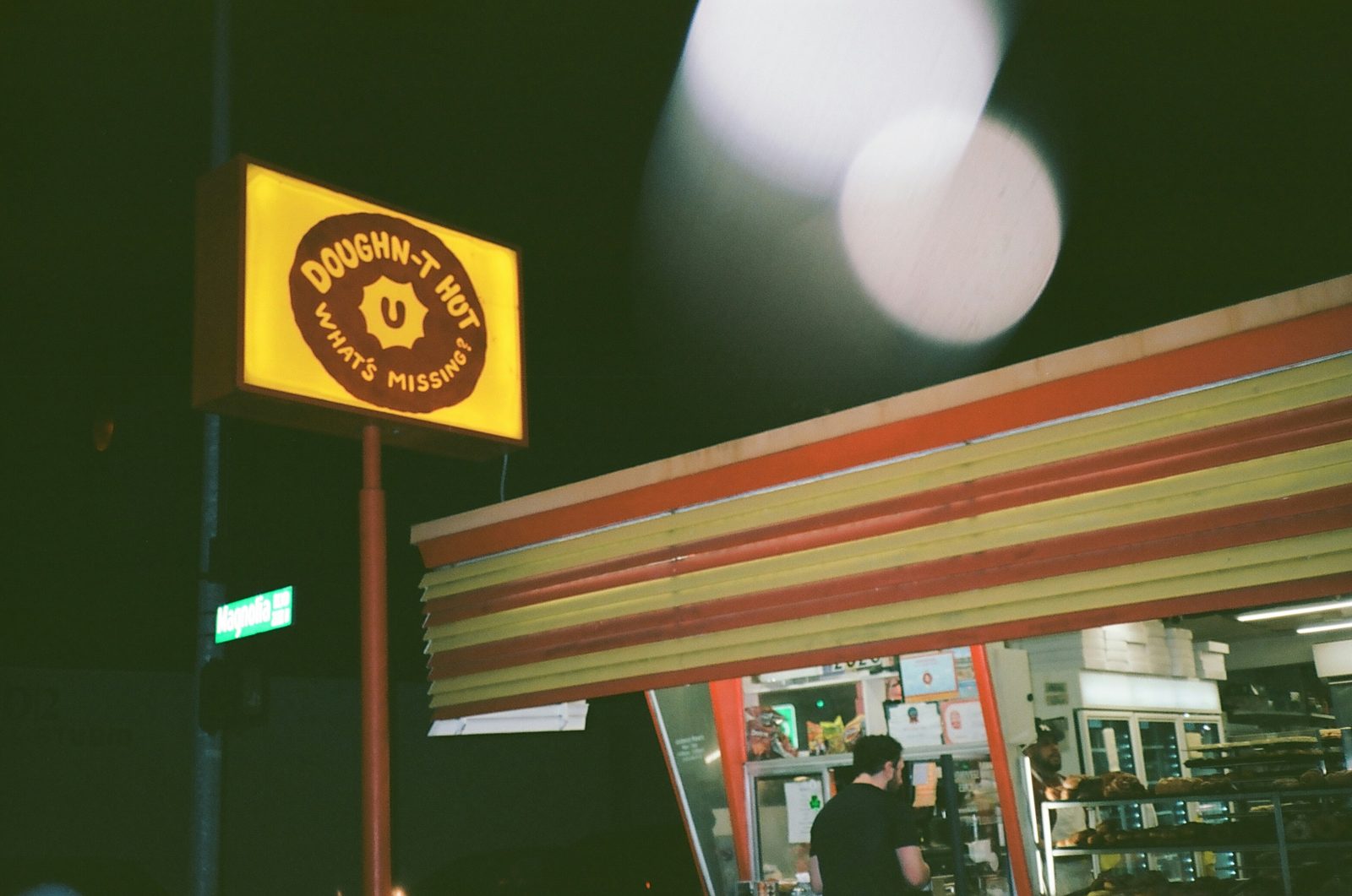 Doughnut shop sign glowing at night above an open storefront