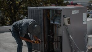 HVAC technician repairing an outdoor AC condenser with its copper refrigerant lines exposed