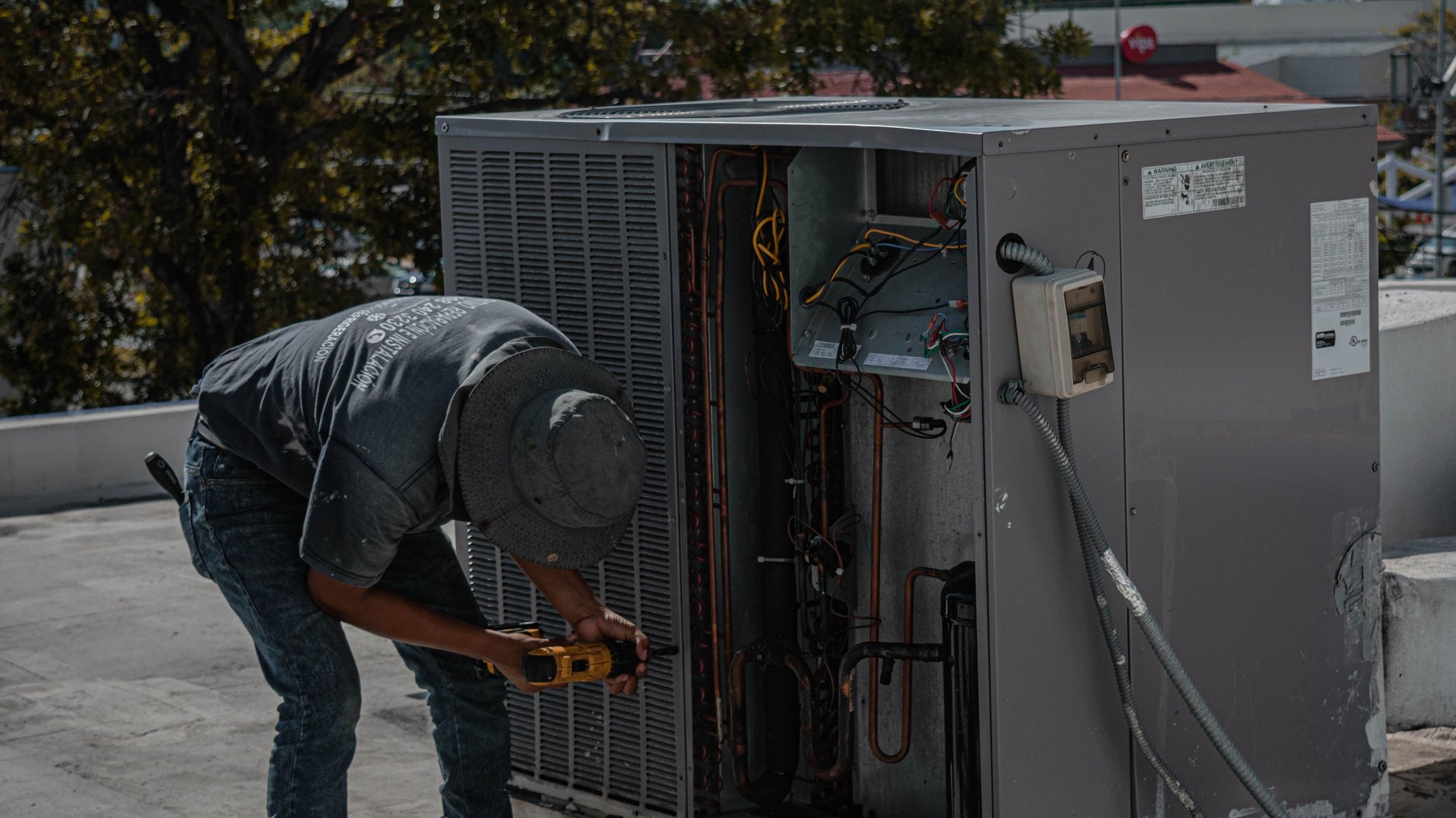 HVAC technician repairing an outdoor AC condenser with its copper refrigerant lines exposed