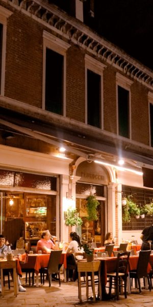 Busy cafe storefront with diners at outdoor tables in the evening
