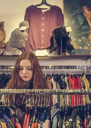Shop owner standing among clothing racks in a small boutique