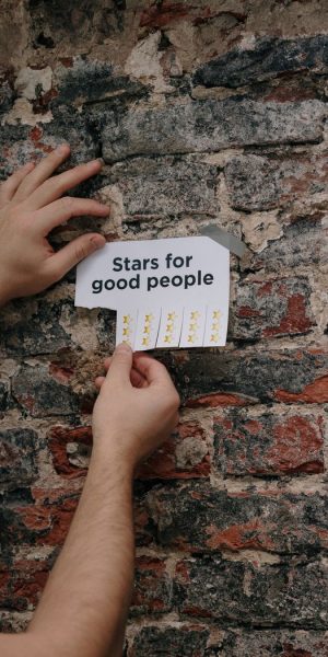 Hand holding a Stars for good people sign against a brick wall